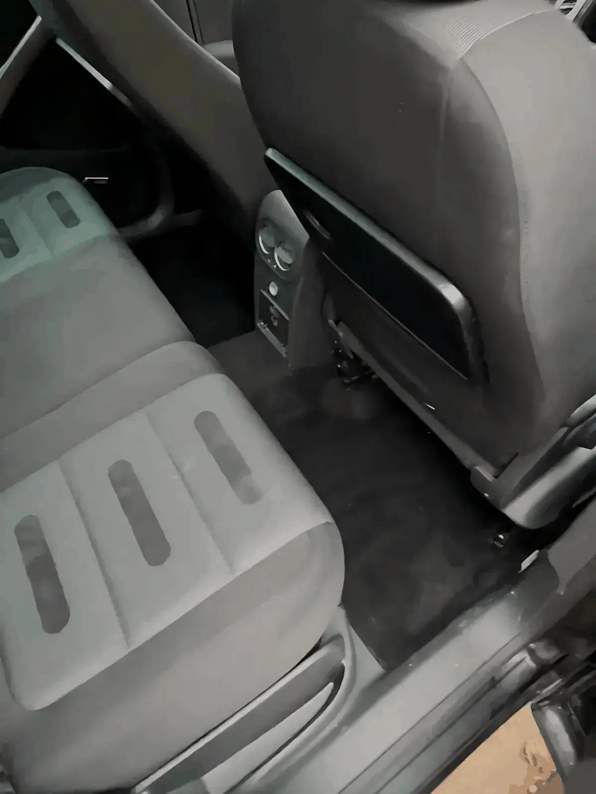 Habitacle d'une voiture avec des sièges arrière en tissu et une moquette parfaitement propres après un nettoyage intérieur professionnel à Argenteuil.