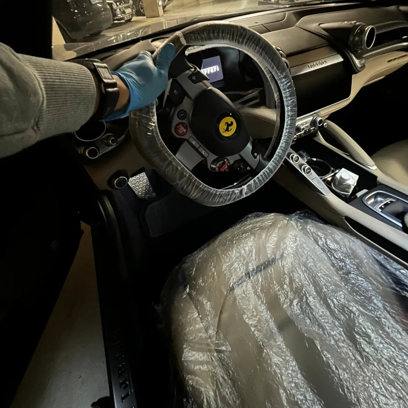 Nettoyage intérieur complet d’une Ferrari à Argenteuil avec protection du volant et des sièges avant la finition.